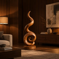 Spiral wood sculpture with a tall flame like swirl and a disc shaped base in an evening living room with walnut wall paneling