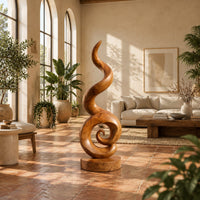Spiral wood sculpture with a tall flame like swirl and a disc shaped base in a bright living room with arched windows and plants