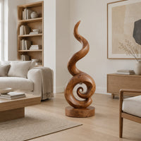 Spiral wood sculpture with a tall flame like swirl and a disc shaped base in a Scandinavian living room with white walls