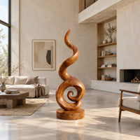 Spiral wood sculpture with a tall flame like swirl and a disc shaped base in a bright open plan living room