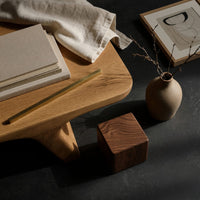 Corner detail of pale splayed leg coffee table beside wood, brass and linen samples