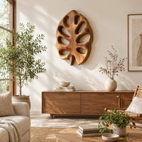 Leaf shaped wall art with open oval cutouts and a short stem in a bright sunroom with green plants