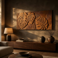 Wood wall art with three carved split leaves in deep relief above a low console in an evening living room