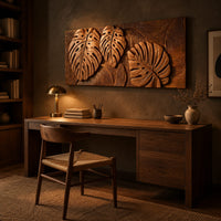 Wood wall art with three carved split leaves in deep relief above a desk in a dark study corner