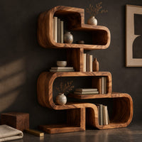 Corner detail of stacked loop bookshelf with offset open cubbies on a flat base beside wood, brass and linen samples