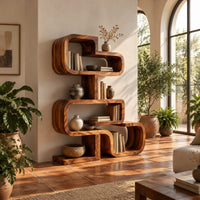 Stacked loop bookshelf with offset open cubbies on a flat base in a bright living room with arched windows and plants