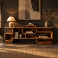 Staggered open shelf console table with interlocking cubbies in a dark entryway at golden hour
