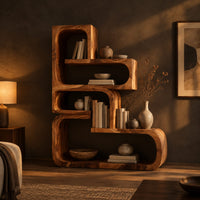 Stepped bookshelf of chunky open cubbies with offset shelves in a dark living room at golden hour