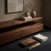 Corner detail of low stepped riser TV console with drawers beside wood, brass and linen samples