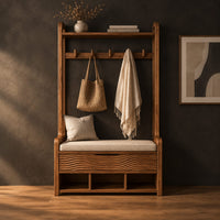 Storage bench with coat pegs, a top shelf, a cushioned seat and open cubbies in a dark studio against a charcoal plaster wall