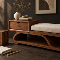 Corner detail of wood bench with a small drawer and an open wave shaped base beside wood, brass and linen samples