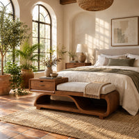 Wood bench with a small drawer and an open wave shaped base in a bright bedroom with arched windows and plants