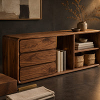 Corner detail of low storage bench with three stacked drawers and open shelf bays beside wood, brass and linen samples