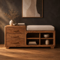 Low wooden bench with three drawers, four open cubbies and a cushioned seat in a dark studio against a charcoal plaster wall