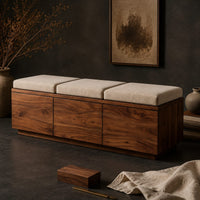 Corner detail of low wooden bench with three seat cushions and a three panel front beside wood, brass and linen samples
