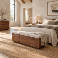 Low wooden bench with three seat cushions and a three panel front in a bright open plan bedroom