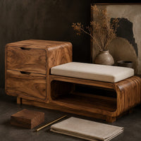 Corner detail of storage bench with a two drawer end, cushioned seat and open shelf beside wood, brass and linen samples