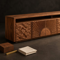 Corner detail of tv stand with a carved sunburst center and wave relief side panels beside wood, brass and linen samples