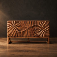 Sideboard with sunburst carving across the front on a slim open frame base in a dark studio against a charcoal plaster wall
