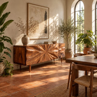 Wood sideboard with a sunburst grain pattern and tapered legs in a bright dining room with arched windows and plants