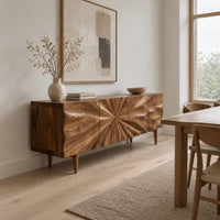 Wood sideboard with a sunburst grain pattern and tapered legs in a Scandinavian dining room with white walls