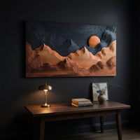Sunrise mountain wall sculpture with a dark carved sky above a desk in a dark study corner