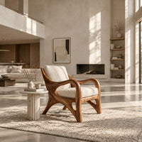 Wooden armchair with sweeping looped arms and soft cream cushions in a bright open plan living room