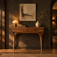 Console table with two front panels and sweeping tapered legs in a dark entryway at golden hour