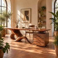 Long desk with a swooping loop base and a wave carved cabinet in a bright home office with arched windows and plants