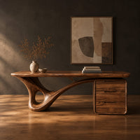 Desk with a looping sculpted leg and a three drawer pedestal in a dark studio against a charcoal plaster wall