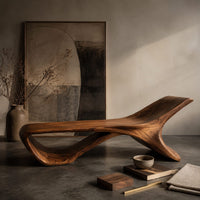 Corner detail of low sweeping bench with an open loop underside and a raised end beside wood, brass and linen samples