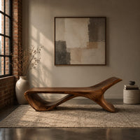 Low sweeping bench with an open loop underside and a raised end in an industrial loft entryway with exposed brick