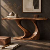 Corner detail of console table with a slim top on one sweeping sculpted pedestal beside wood, brass and linen samples
