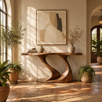 Console table with a slim top on one sweeping sculpted pedestal in a bright entryway with arched windows and plants