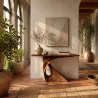 Console table with a slim top on a single pedestal pierced by a teardrop in a bright entryway with arched windows and plants