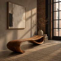 Long wooden bench shaped like a ribbon with a rolled end in an industrial loft entryway with exposed brick