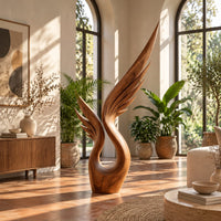 Wood sculpture of a swept wing with carved feather grooves and an open loop in a bright living room with arched windows and plants