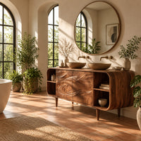 Bathroom vanity cabinet with swirl carved doors, open end shelves and slim legs in a bright bathroom with arched windows and plants