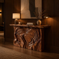 Console table with a swirl carved front and a thick natural edge top in an evening entryway with walnut wall paneling
