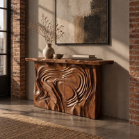Console table with a swirl carved front and a thick natural edge top in an industrial loft entryway with exposed brick
