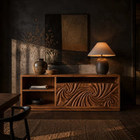 Sideboard with two swirl carved doors and open shelf bays at one end in a dark dining room at golden hour