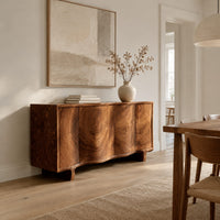 Wavy front sideboard with four panels of swirling wood grain in a Scandinavian dining room with white walls