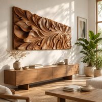 Wide wooden relief panel carved with swirling overlapping leaves in a bright sunroom with green plants