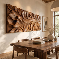 Wide wooden relief panel carved with swirling overlapping leaves beside a dining table in natural light