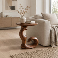 Round side table on a swirling pedestal with a curled foot in a Scandinavian living room with white walls
