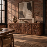 Long sideboard with four doors carved in deep swirling ripples in an industrial loft dining room with exposed brick