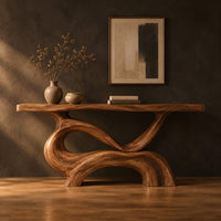 Console table with a slim plank top on a swirling sculpted base in a dark studio against a charcoal plaster wall