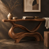 Corner detail of console table with a slim plank top on a swirling sculpted base beside wood, brass and linen samples