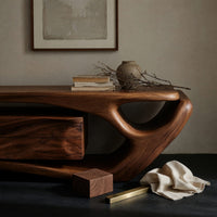 Corner detail of TV cabinet with a sweeping cantilever top over drawers beside wood, brass and linen samples