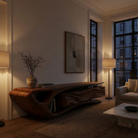 TV cabinet with a sweeping cantilever top over drawers in an evening room lit by two lamps
